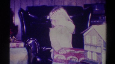 1973: a bleary eyed child begins to open gifts on christmas morning as family