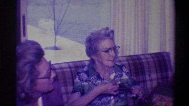 1973: grandmother sits on couch watching children open christmas presents NEW
