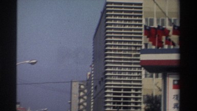 1982: bustling traffic on a busy city street surrounded by large buildings