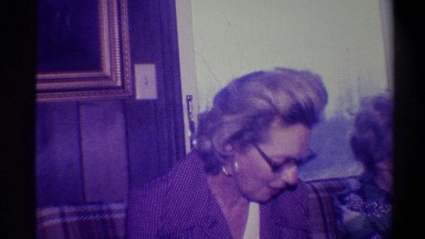 1973: Older Woman With Glasses Receiving Necklace as Gift for Christmas