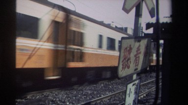 1982: train moving on a track with a sign adjacent written in asian language
