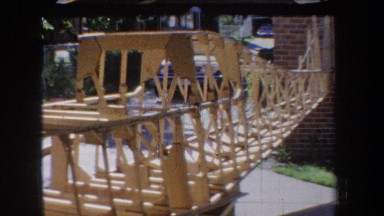 1965: wooden frame of an uncompleted boat near a brick house VOLMER YUCAIPA