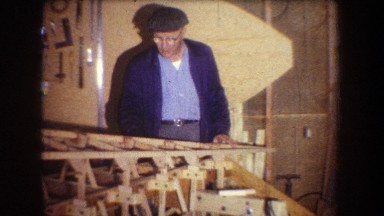 1965: Older Man Checks and Glues Final Pieces of Wooden Structure