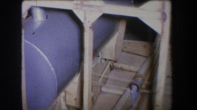 1965: A Blueish-Gray Cylindrical Tank Supported in a Wooden Frame Structure