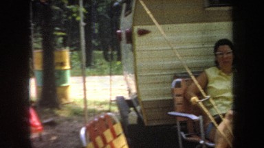 1968: a family sits outside of a camper in the woods on a sunny day MICHIGAN