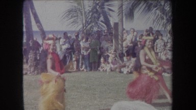 1969: pretty ladies wag their hips as they dance in colorful grass skirts.