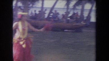 1969: hawaiian women in grass skirts dancing the hula in front of a group of