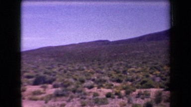 1958: overview of a large field with rock formations and a welcome sign ARIZONA