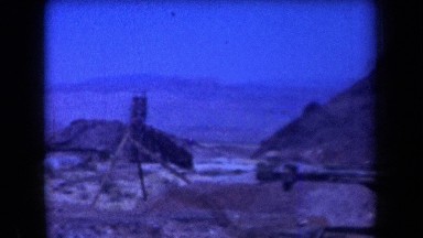 1958: panorama of a dozen homes in a desert with mountains in the distance