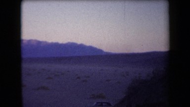 1958: a panning view of a mountain range in the distance and campers set up in