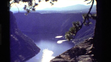 1980: A Canyon Cut Through by a River with the Sun Reflecting Off of It Behind