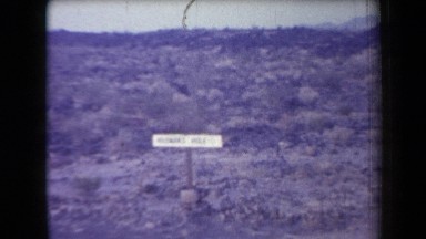 1958: Scientists Examine Sandy and Brush-Filled Slope Between Parked Cars and Signs