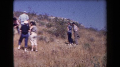 1958: A Group of People Climbing a Hill Under a Clear Blue Sky in Arizona