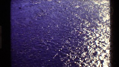 1980: A Forward Panning Scene of a Flowing Wide River Surrounded by Tall Grass