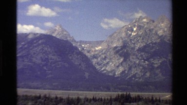 1980: a dark mountain landscape overlooking a forest on a sunny day WESTERN USA