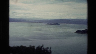 1981: panoramic view of an ocean with a rock area jutting into the sea with