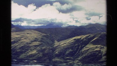 1982: a high view of a mountain range clearing a cloudy and blue sky and a