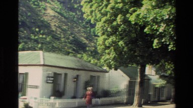 1982: row of small similar houses side by side with a hillside directly behind