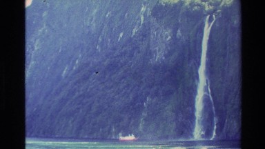 1982: a woman on a viewing deck looking at a mountain range and a waterfall NEW