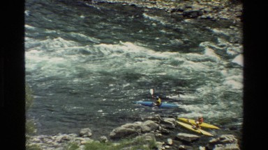 1980: five kayak riders are riding toward opposite direction of river to cross