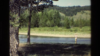 1980: man wades through a lake in a beautiful forest. GRAND TETON WYOMING