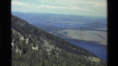 1980: views from atop a forested ridge looking down at a large valley with lakes