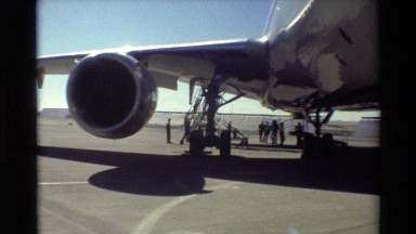 1981: group of men gathered underneath a large airplane, discussing something to