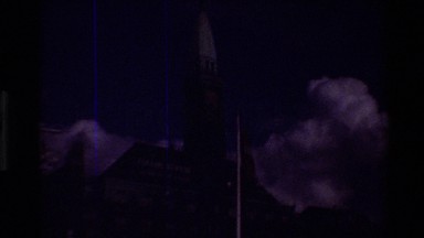 1982: A Flag Waves in the Wind in Front of a Large Brick Building with a Clock