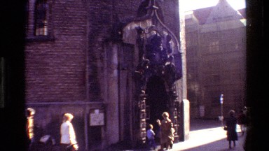 1982: Pedestrians Pass Building Where Women and Children Stand at Ornate Arched Entry