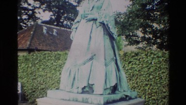 1982: the statue of a lady stands erect near to a small building DENMARK
