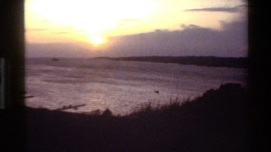 1982: sunset through clouds showing oranges, yellows over mountains DENMARK