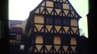 1983: a pan of the front of buildings that look to maybe be an old church in
