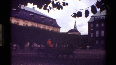 1983: person in orange riding horse and buggy through courtyard. DENMARK