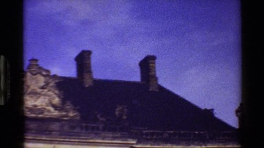1983: a camera panning a rooftop of an old building that has ornate statues