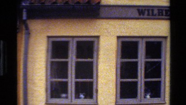 1982: An Old Stucco Building with European Style Windows and a Sign on Its Roof