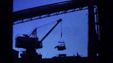 1971: crane lifting a bulldozer into the air at construction site MAINE