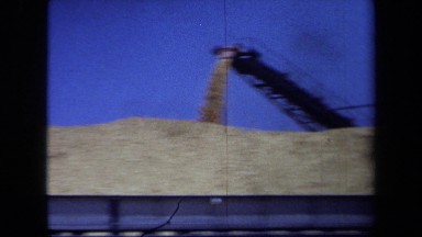 1971: a camera zooms out from a machine pouring gravel out MAINE