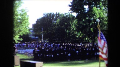 1971: a crowd of young people gathered together in black caps and gowns
