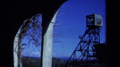 1971: a wooden watchtower viewed from under an archway. MAINE