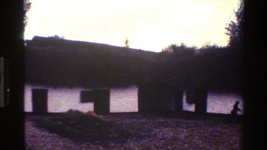 1983: parents and child walking outdoors near rows of housing by some trees