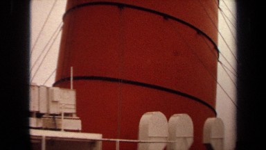 1971: a huge funnel of a ship painted in orange and black and fitted with horns