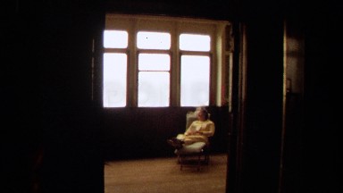 1971: an elderly woman reclining in a chair next to a window LONG BEACH