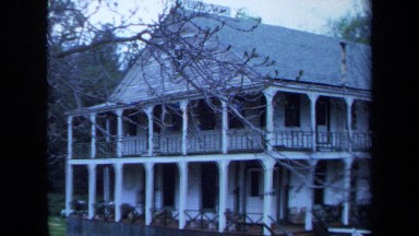 1971: overview of a two story white house in the woods. MAINE