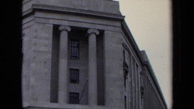 1970: a red light signals for cars to stop outside of a white stone building