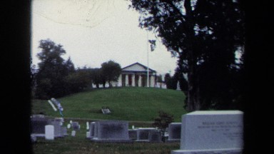 1970: stately columned building overlooks headstones, and young group visits