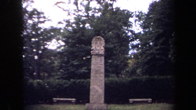 1970: stone column is topped with double row of curved bands around oval center