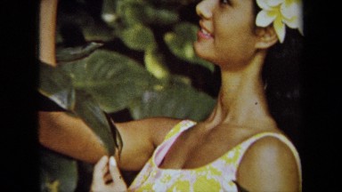 1971: A Woman in Floral Print Holding a Hawaii Travel Poster