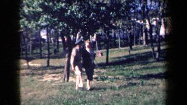 1959: Man in Uniform and Woman Walking Through Grass in New York
