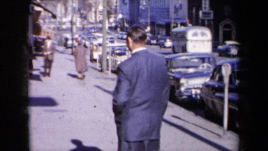 1959: man in suit walking along parked cars NEW YORK