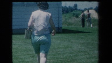 1959: A Woman Walking Toward Men Playing Ball in New York Backyard